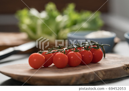 Ripe cherry tomatoes on a branch on wood board Ripe cherry tomatoes on a branch on wood board 69452053
