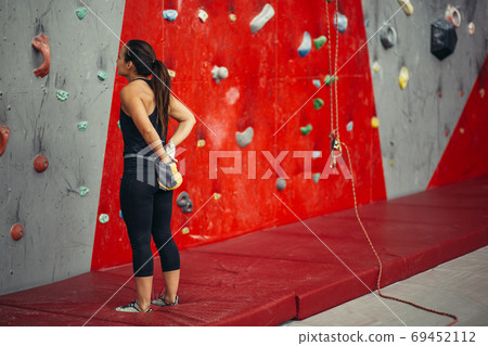 Rear view of sportswoman looking at climbing wall Rear view of sportswoman looking at climbing wall 69452112