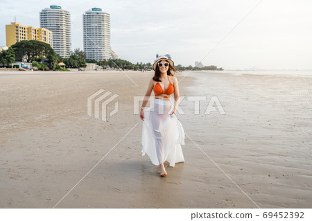 cheerful woman in bikini walking on sea beach 69452392
