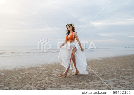 cheerful woman in bikini walking on sea beach 69452395