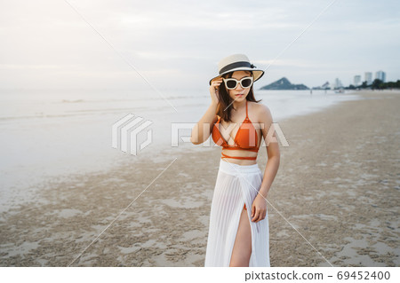 cheerful woman in bikini standing at sea beach 69452400