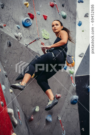 Sporty young woman training in a colorful climbing gym. Free climber girl climbing up indoor 69452686