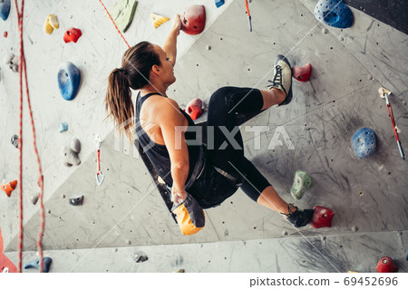 Sporty young woman training in a colorful climbing gym. Free climber girl climbing up indoor 69452696