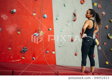 Rear view of sportswoman looking at climbing wall 69452813