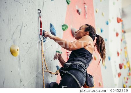 Beautiful young woman taking a big step up an artificial wall Beautiful young woman taking a big step up an artificial wall 69452829