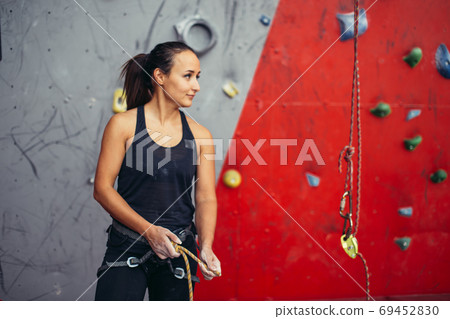 Woman climber tying rope in knot and preparing to climb. Climbing equipment Woman climber tying rope in knot and preparing to climb. Climbing equipment 69452830