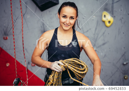 Climber girl in safety harness tying rope in eight knot and preparing to climb, view of hands Climber girl in safety harness tying rope in eight knot and preparing to climb, view of hands 69452833