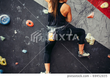 Beautiful young woman taking a big step up an artificial wall Beautiful young woman taking a big step up an artificial wall 69452835