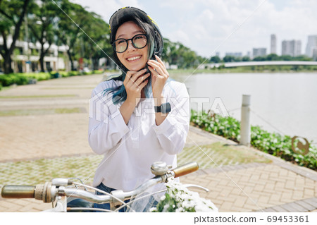 Chinese woman putting on helmet Chinese woman putting on helmet 69453361