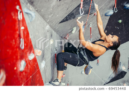 Sporty young woman training in a colorful climbing gym. Free climber girl climbing up indoor 69453448
