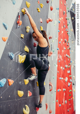 Sporty young woman training in a colorful climbing gym. Sporty young woman training in a colorful climbing gym. 69453508