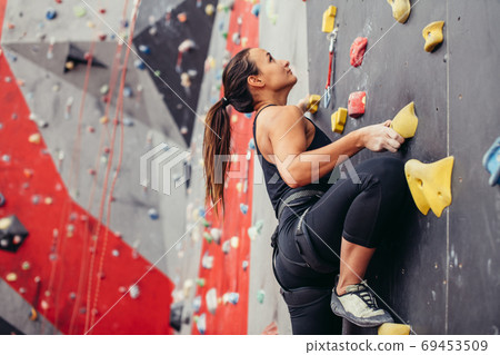 Young climber woman climbing on practical rock in climbing center, bouldering 69453509