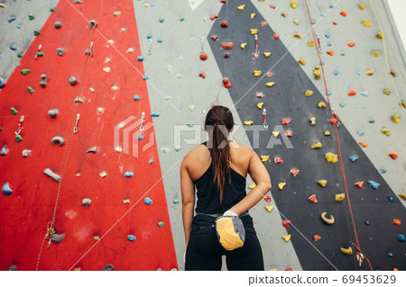 Sportswoman looking at climbing wall in gym Sportswoman looking at climbing wall in gym 69453629