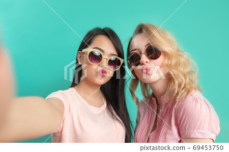 Close up faces portrait of happy multiethnic female friends isolated over blue Close up faces portrait of happy multiethnic female friends isolated over blue 69453750