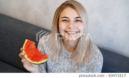 Young attractive woman eating watermelon. Woman looking at camera and smiling Young attractive woman eating watermelon. Woman looking at camera and smiling 69453817