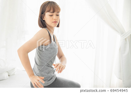 The woman after waking up in bedroom, Twisting the body from drowsiness and fatigue 69454945