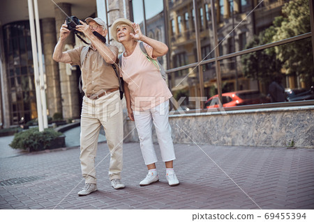 Male pensioner in a cap photographing the city sights 69455394