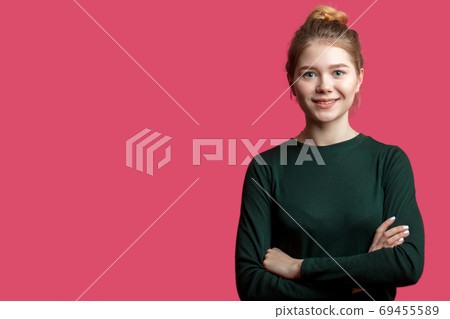 Pretty young woman with hair bun looking at camera with smile over pink 69455589