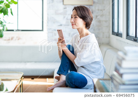 在客廳裡操作智能手機的中年婦女 69456075