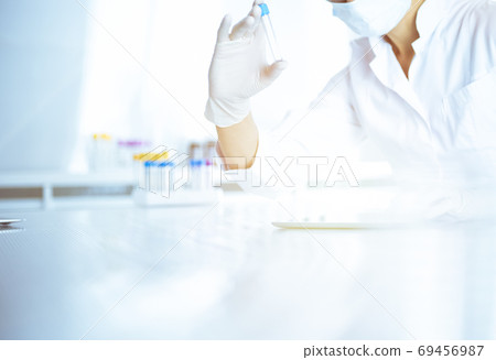 Female laboratory assistant analyzing a blood sample at hospital. Medicine, health care and researching concept 69456987