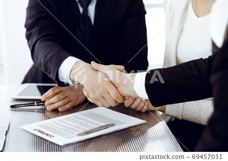 Business people shaking hands after contract signing in modern office. Teamwork, partnership and handshake concept Business people shaking hands after contract signing in modern office. Teamwork, partnership and handshake concept 69457031