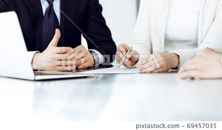 Business people discussing contract working together at meeting in modern office. Unknown businessman and woman with colleagues or lawyers at negotiation Business people discussing contract working together at meeting in modern office. Unknown businessman and woman with colleagues or lawyers at negotiation 69457035