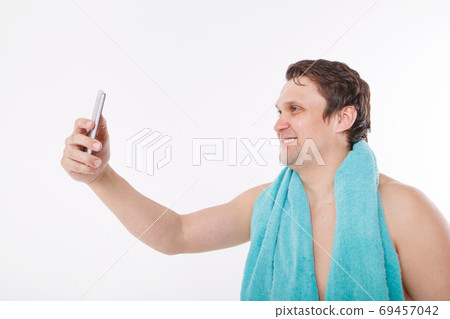 the guy takes a selfie after morning procedures. A man looks at the phone camera. Smooth-shaven face. Blue towel around her neck. Man and modern technologies. the conversation via video link the guy takes a selfie after morning procedures. A man looks at the phone camera. Smooth-shaven face. Blue towel around her neck. Man and modern technologies. the conversation via video link 69457042