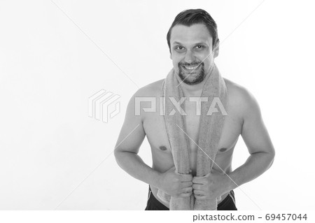 the guy strokes his beard. morning treatments in the bathroom. blue towel around her neck. isolated on a white background. copy space the guy strokes his beard. morning treatments in the bathroom. blue towel around her neck. isolated on a white background. copy space 69457044