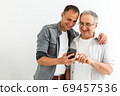Happy two age generations men family old father embracing young grown adult son having fun enjoying using smart phone bonding watching funny social media video using mobile apps 69457536
