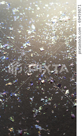 Foil pieces on black background with multi-colored shine. Abstract fashion stock macro photo. 69459871