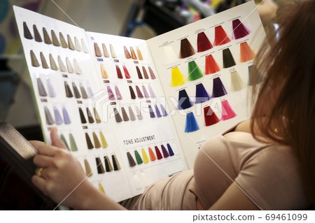 a woman is looking at hair color chart 69461099