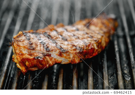 Close up of delicious beef steak on flaming grill. Close up of delicious beef steak on flaming grill. 69462415