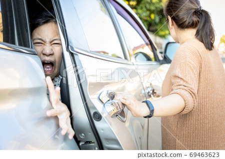 Accident,hand slammed the door,mischievous child girl was pinched her hand or fingers in the car door,asian daughter shouted in pain,woman or mother closed the car door without careful,inadvertently  69463623