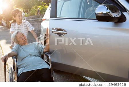 Asian female people enjoying talking on the phone,opening the door car slamming the wheelchair of elderly, inattentive woman crashed into wheelchair of disabled senior woman while opening the door 69463626