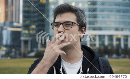 Young man with a cigarette in his mouth, close up 69464770