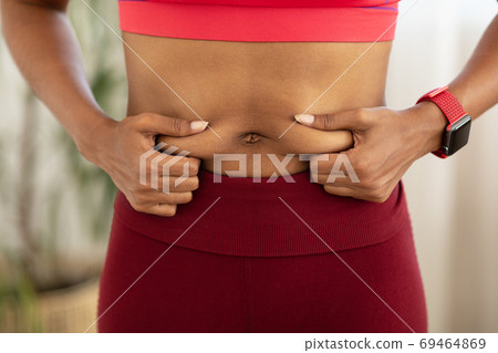 Black Woman Touching Belly Fat Losing Weight Standing Indoors, Cropped 69464869