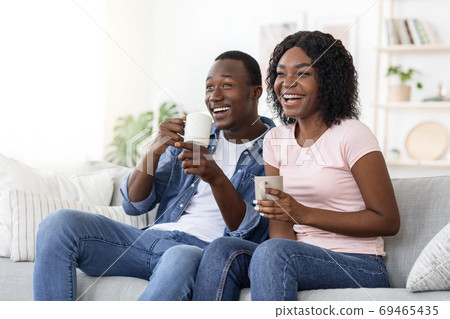 African lovers drinking tea and watching comedy at home 69465435