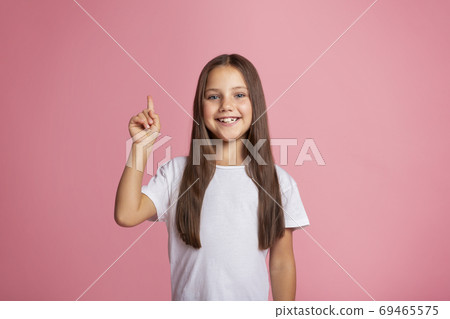 Little beauty casual style. Smiling girl points finger up 69465575