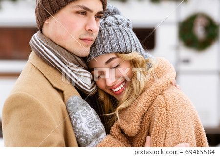 Young Affectionate Couple Enjoying Winter Day Together, Hugging And Bonding Outdoors Young Affectionate Couple Enjoying Winter Day Together, Hugging And Bonding Outdoors 69465584