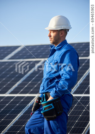 Electrician mounting solar panel on roof of modern house 69465903