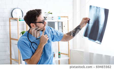 Male veterinary surgeon looking at xray at animal hospital 69465982
