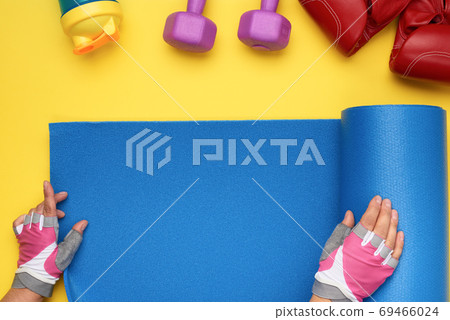 female hands in sports gloves unfold a sports mat on a yellow ba female hands in sports gloves unfold a sports mat on a yellow ba 69466024
