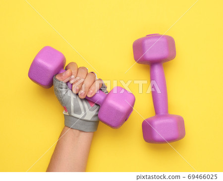 female hand in a pink sports glove holds a purple one kilogram d 69466025