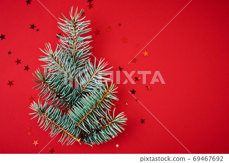 Christmas composition. Fir branches in a shape of christmas tree with festive confetti on red background with copy space Christmas composition. Fir branches in a shape of christmas tree with festive confetti on red background with copy space 69467692