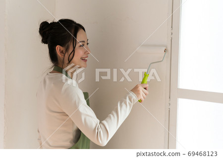 A woman who paints the walls of a house with DIY A woman who paints the walls of a house with DIY 69468123