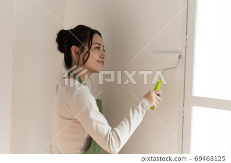A woman who paints the walls of a house with DIY A woman who paints the walls of a house with DIY 69468125
