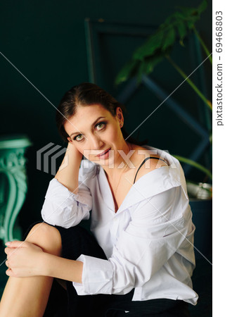 Portrait of a beautiful young woman in a white shirt and black pants in the Studio Portrait of a beautiful young woman in a white shirt and black pants in the Studio 69468803