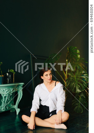 Portrait of a beautiful young woman in a white shirt and black pants in the Studio Portrait of a beautiful young woman in a white shirt and black pants in the Studio 69468804