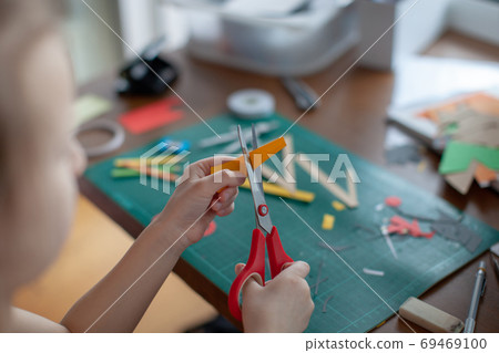 A seven-year-old girl cuts out with a scissors yellow paper. A seven-year-old girl cuts out with a scissors yellow paper. 69469100