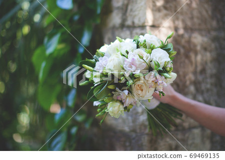 The bride holds a bouquet in her hands.  69469135